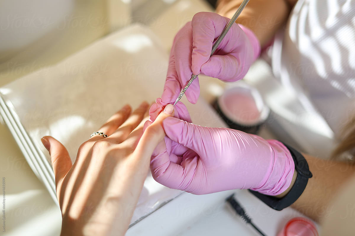 A manicurist treats a woman\'s nails and cuticles in a beauty salon