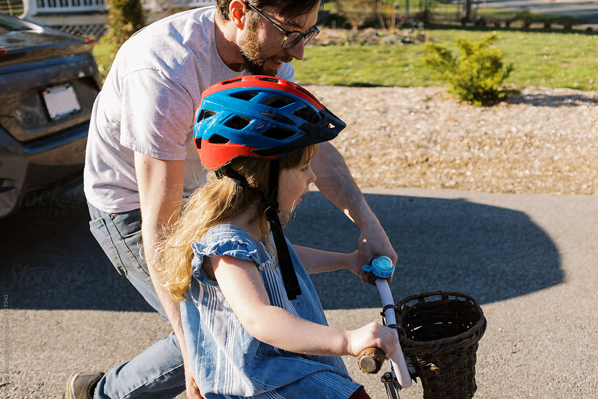 Dad helping his happy daughter to learn to ride a bicycle