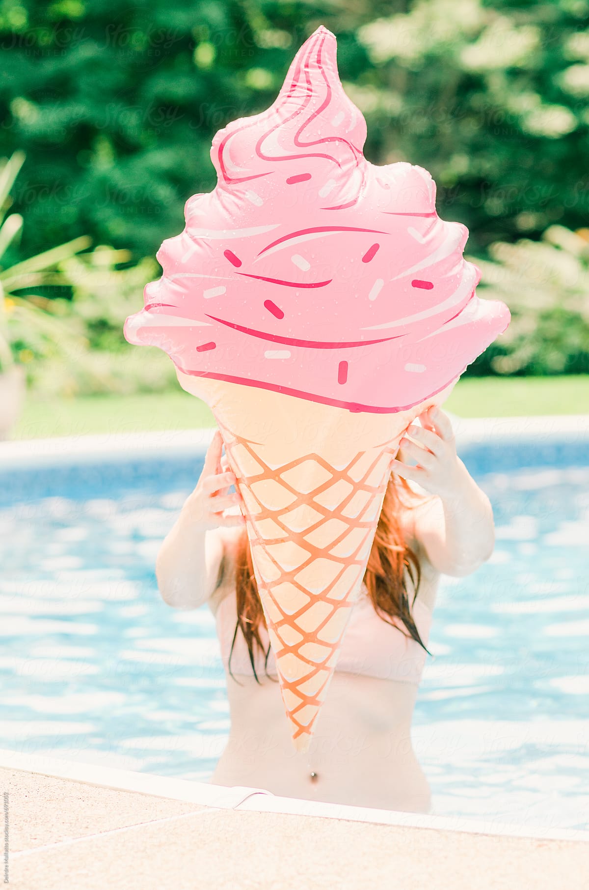 girl holds pink ice cream cone pool float