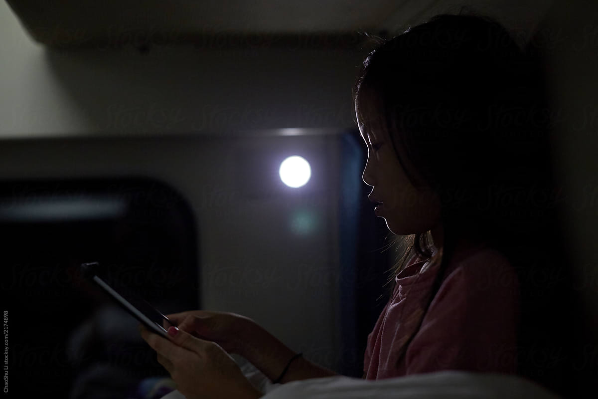 Asian little girl on the train, looking at tablet
