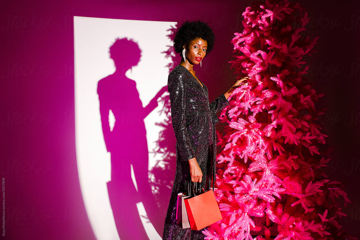 Fashionable woman wearing evening bright suit near Christmas tree