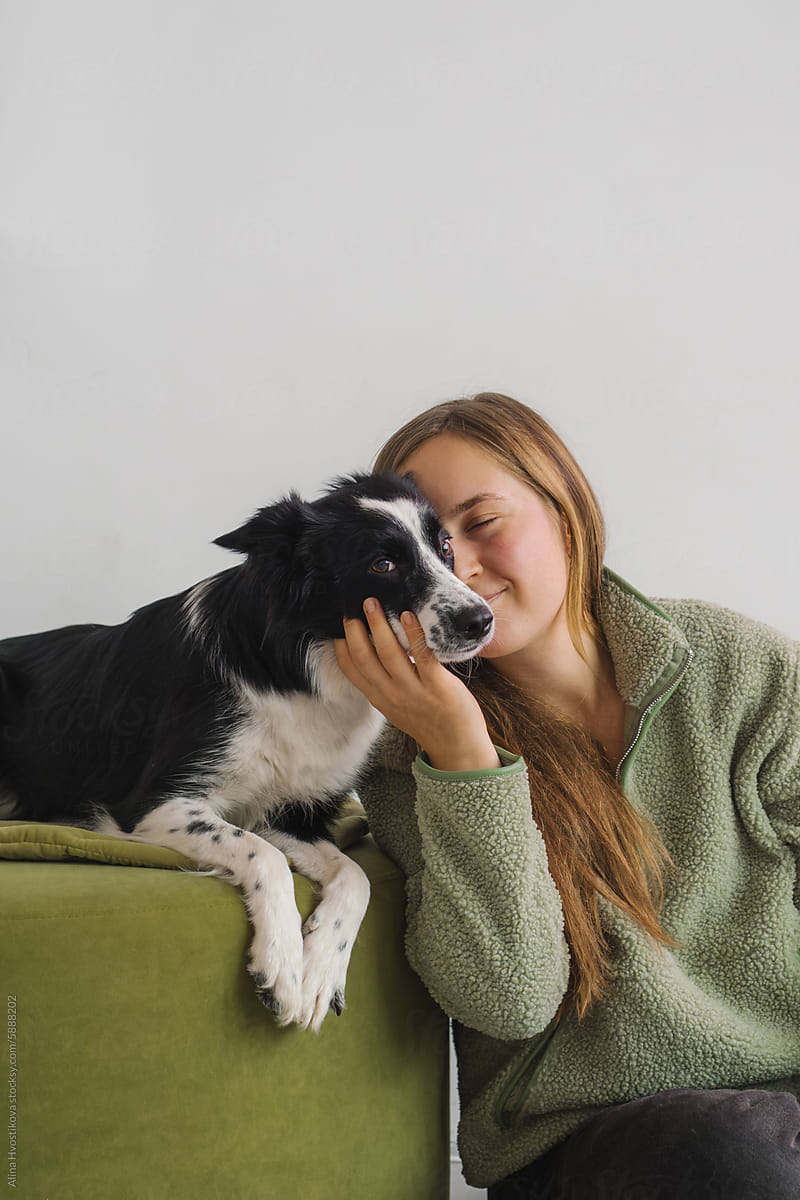 Positive young woman with dog on couch at home