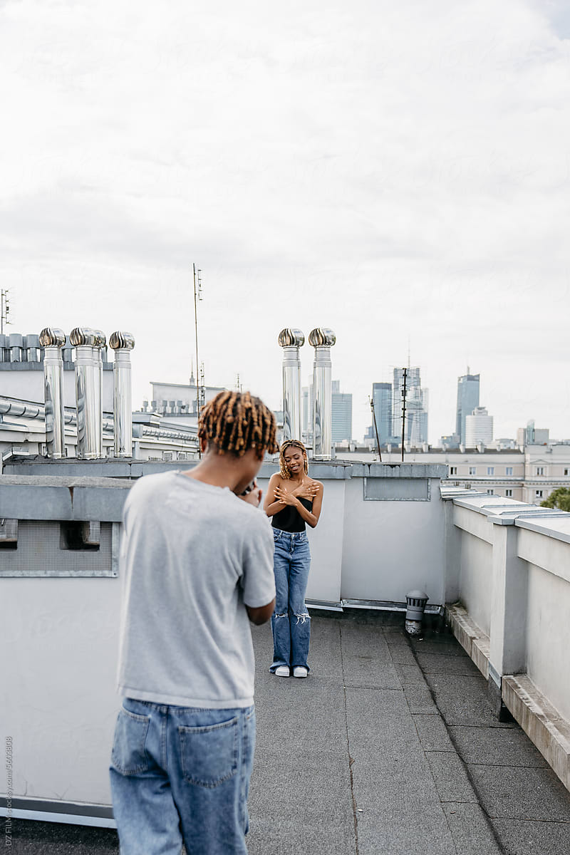 A man takes a picture of a woman on the roof