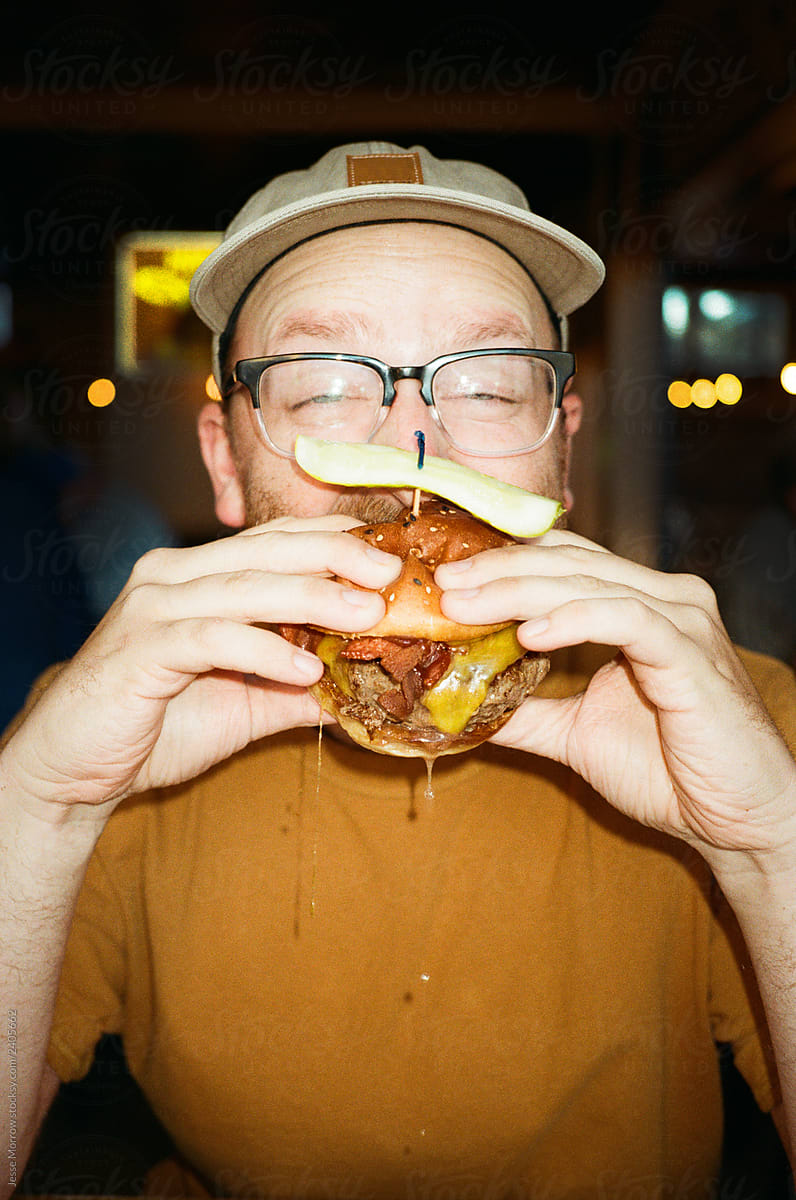 young male eats larger hamburger
