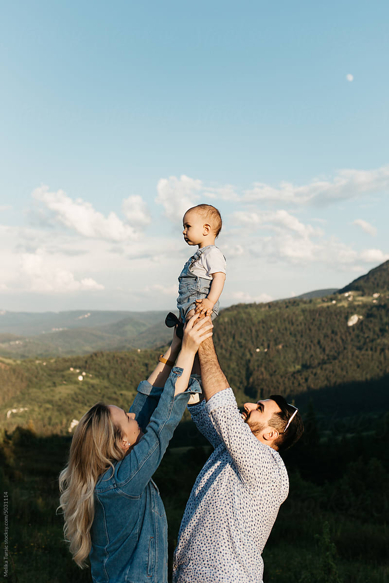 Couple out in nature playing and holding their child