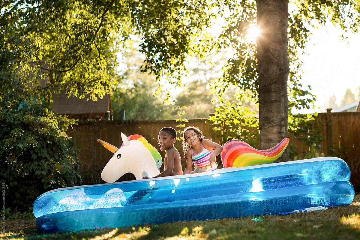 Siblings ride floatie unicorn in pool