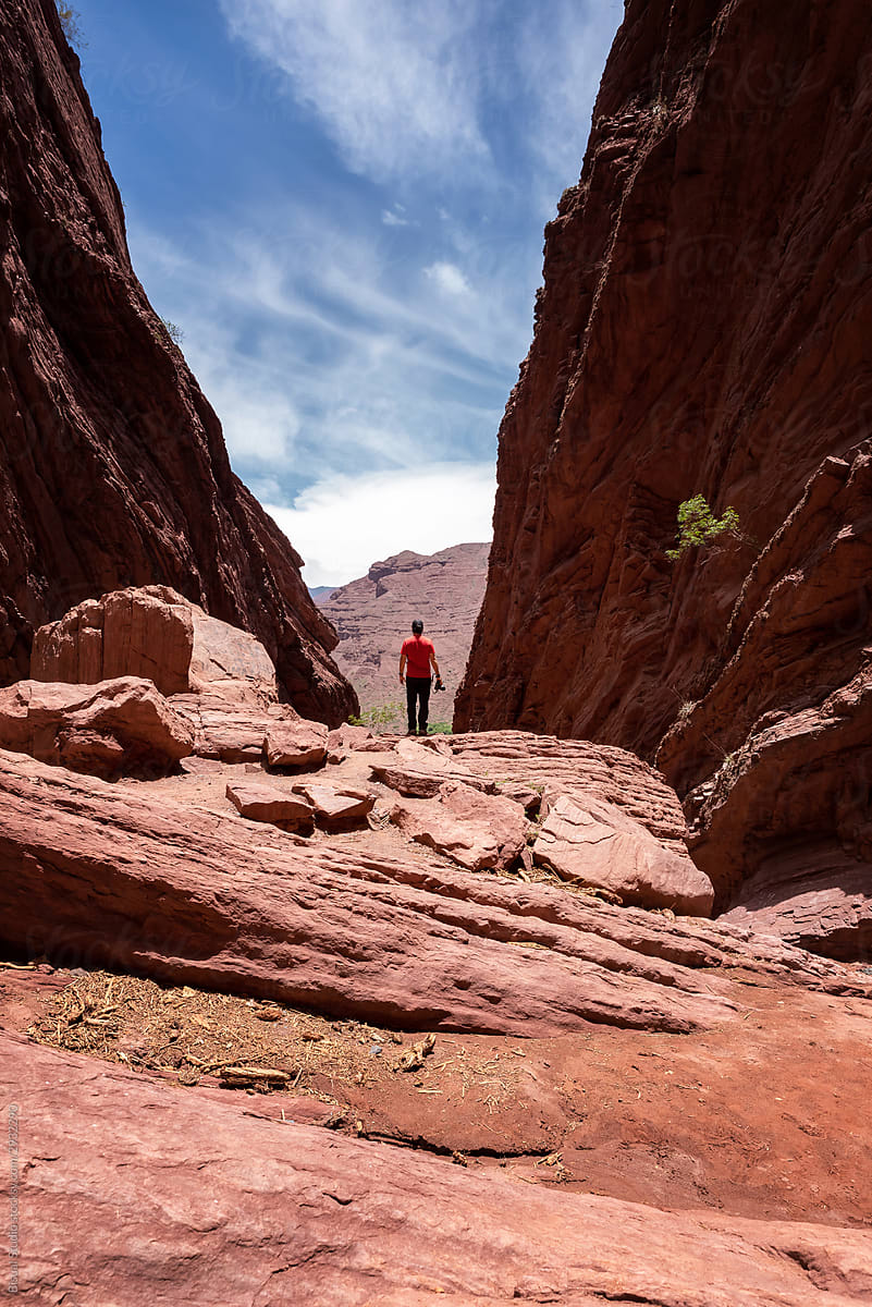 Photographer standing on a rock with a camera taking suroounded by red earth formations