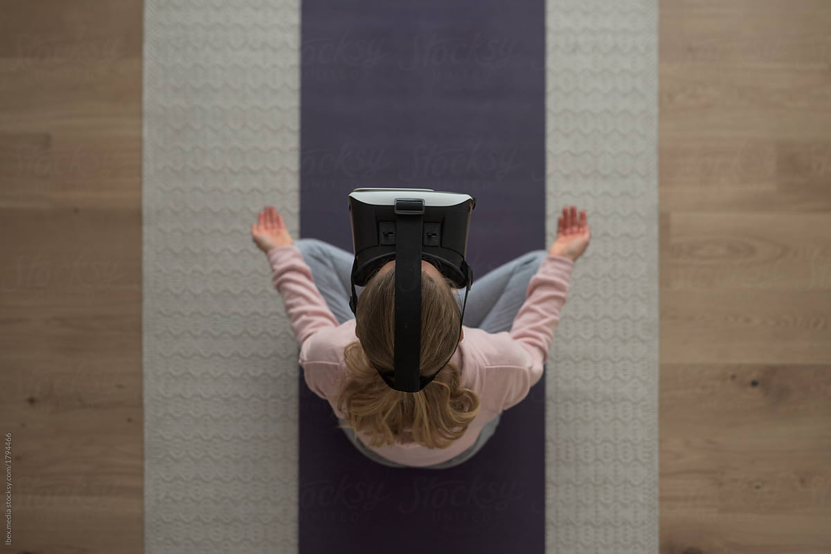 Woman meditating in lotus pose with vr goggles