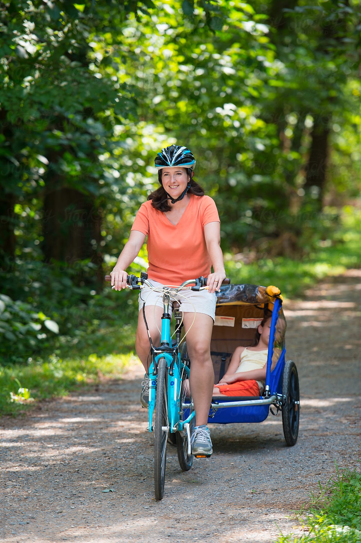 Family Bike Ride: Mother Tows Sleeping Daughter on Wooded Path