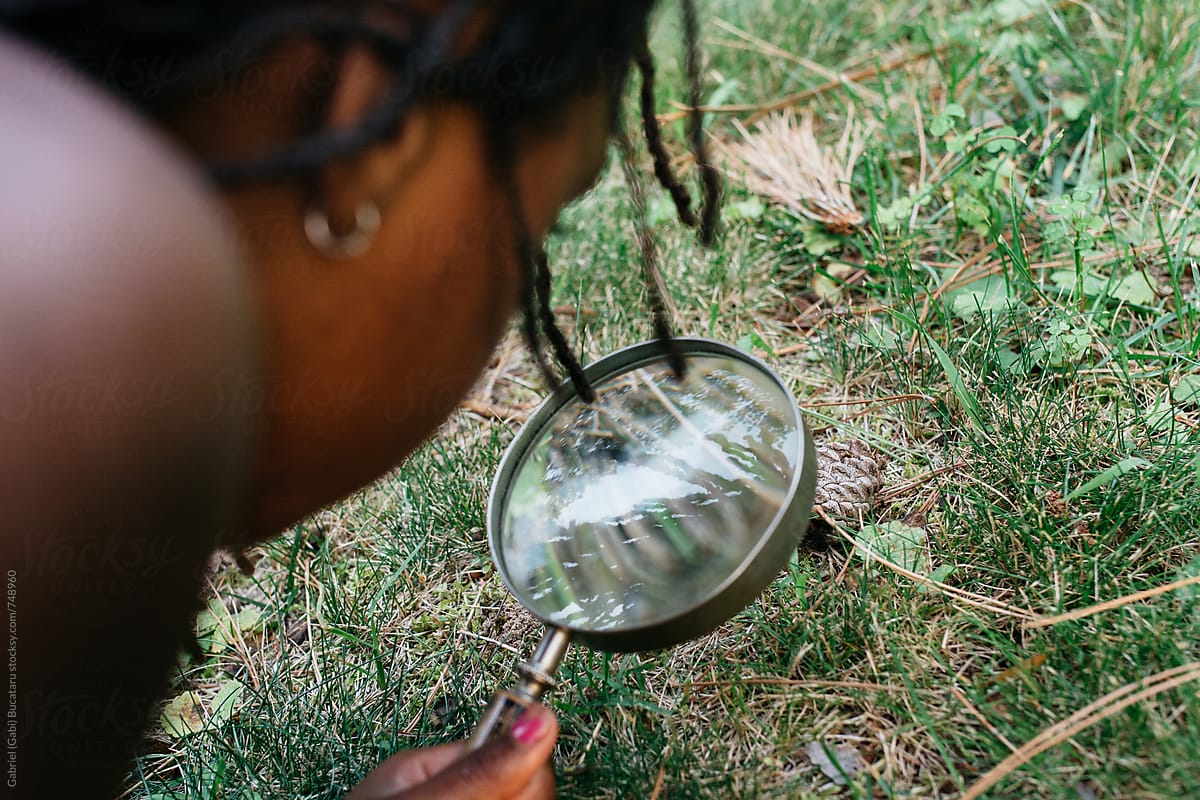 Black girl studying a bug through a magnifying glass