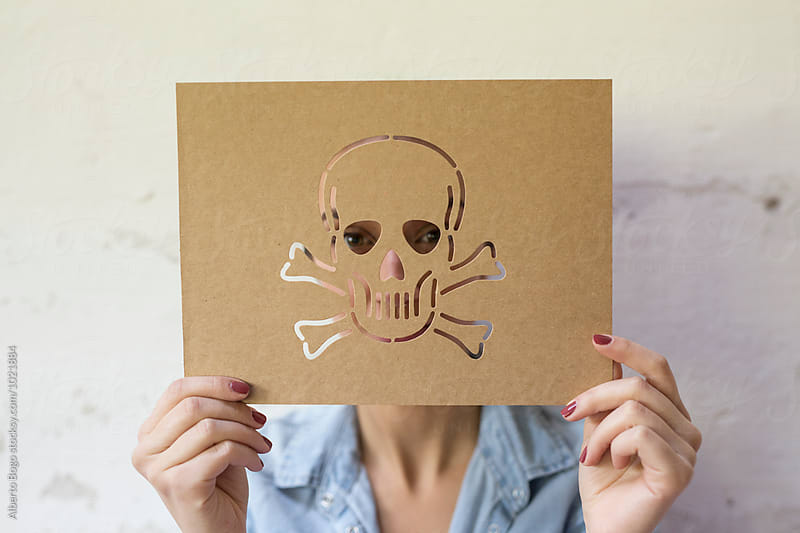 Unrecognizable person holding paperboard with carved skull