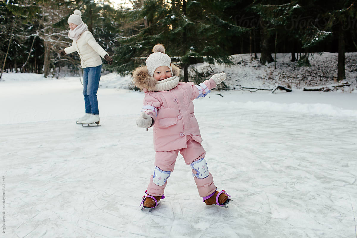 Happy little child skating on ice in forest