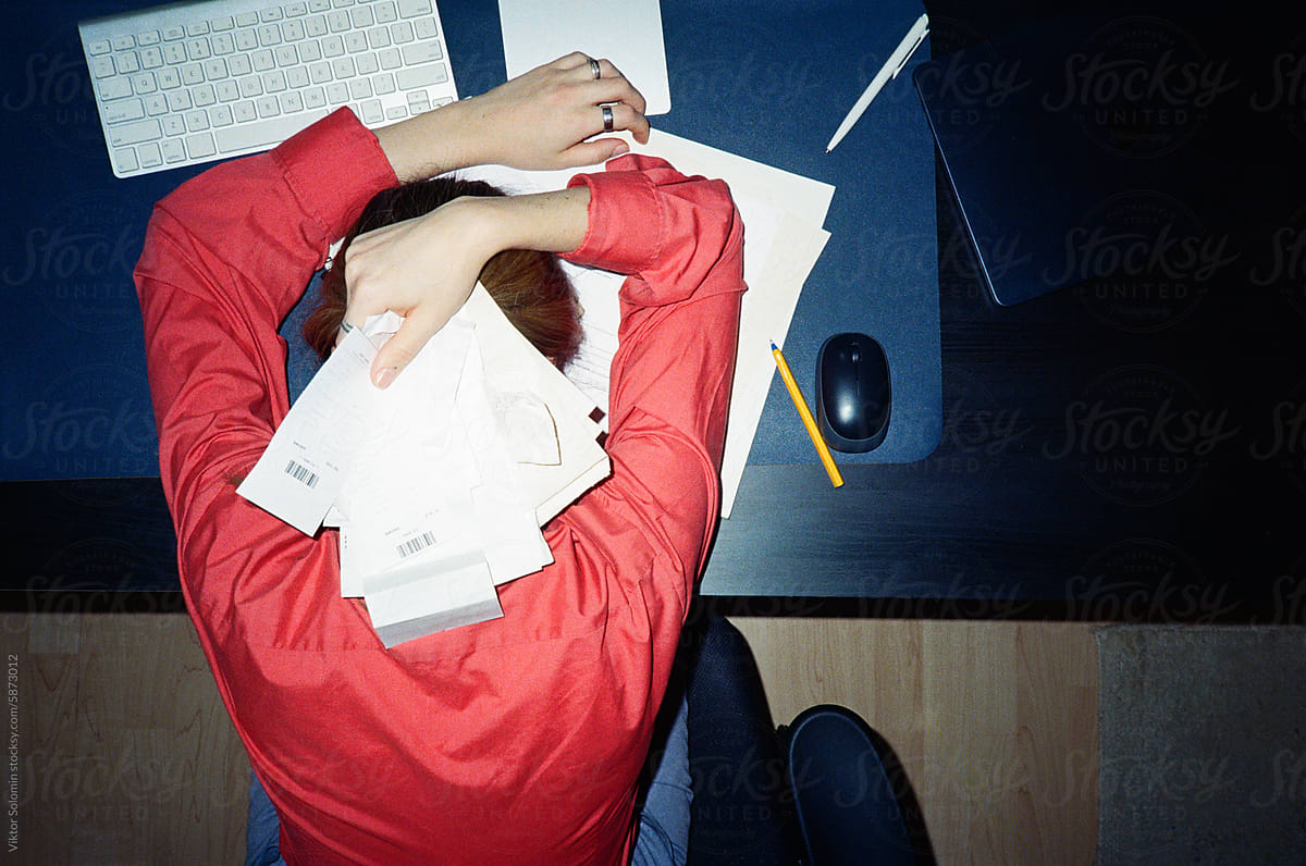 Crop female office employee tired and exhausted of receipts managing