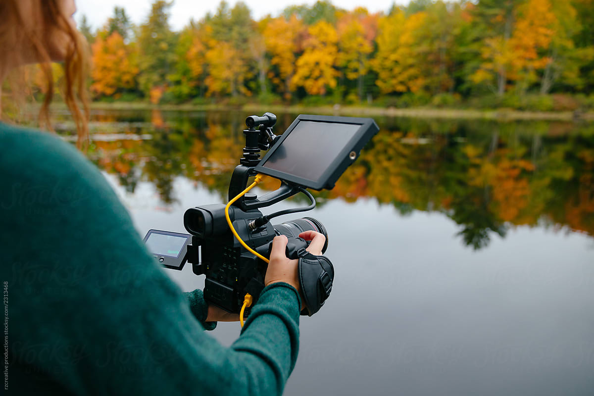 Videographer filming outdoors in fall.