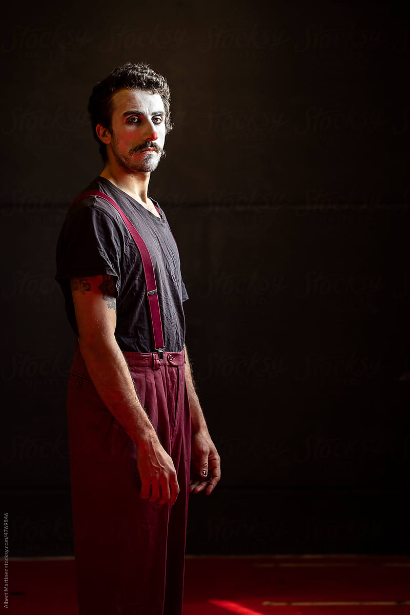 Serious male clown with makeup gazing at camera