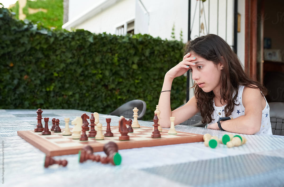 Stressed girl playing chess in yard