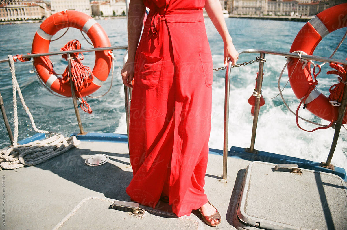 Woman in red dress on the boat in a middle of a sea
