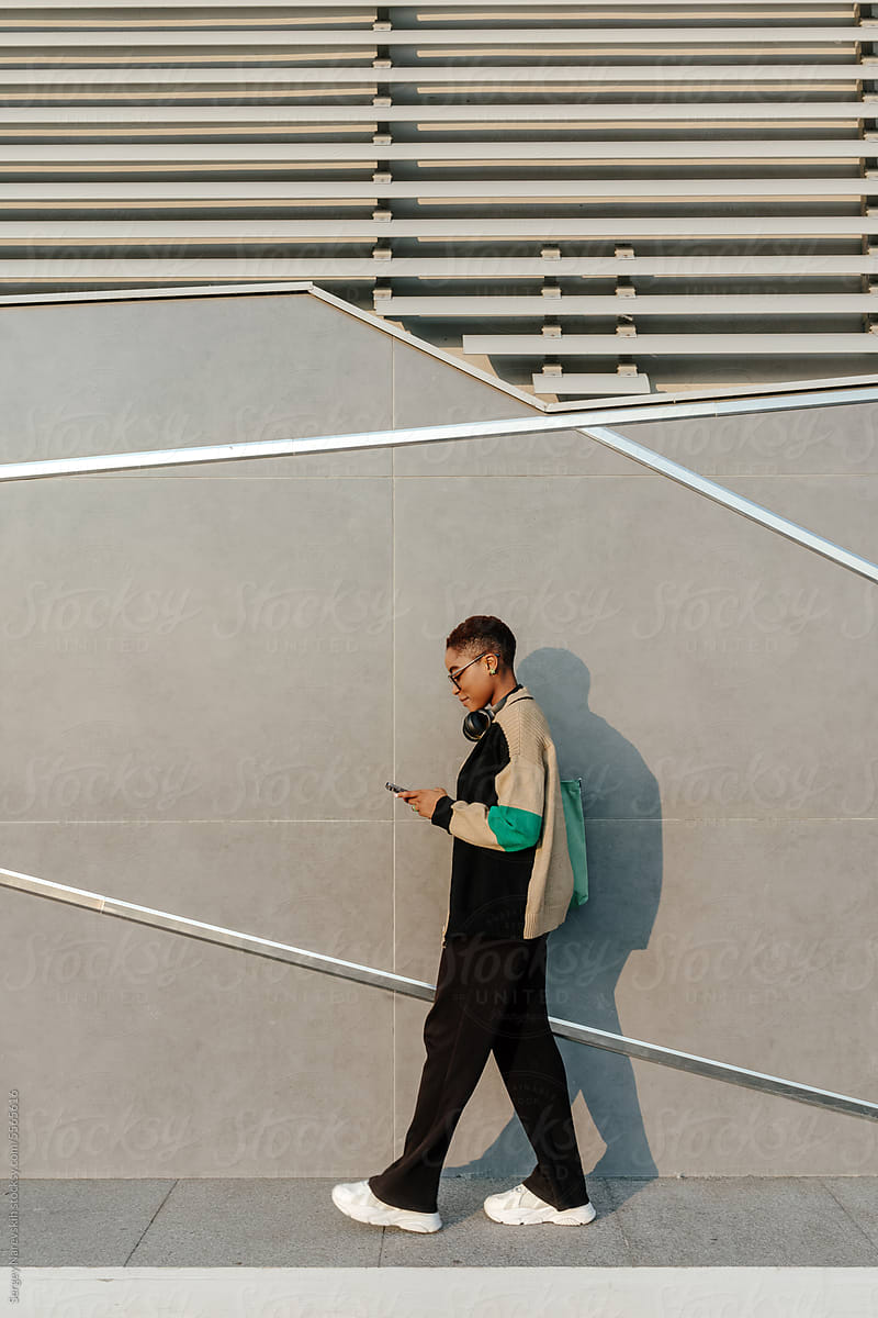 Woman using smartphone while walking on sidewalk