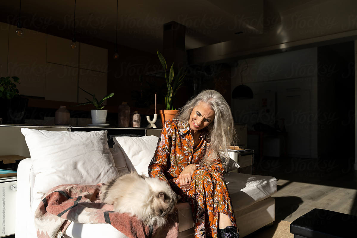 Mature woman brushing cat\'s hair at home