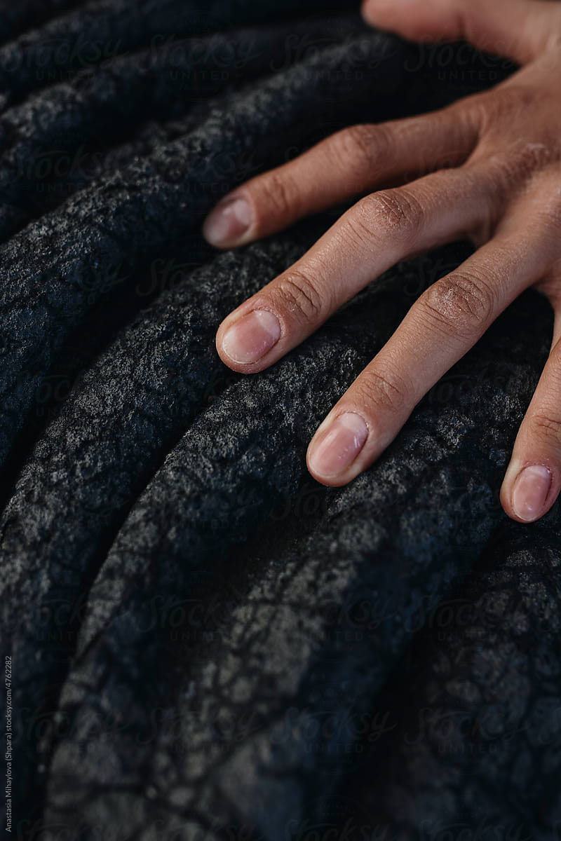 Close-up female fingers on black solid lava in Iceland