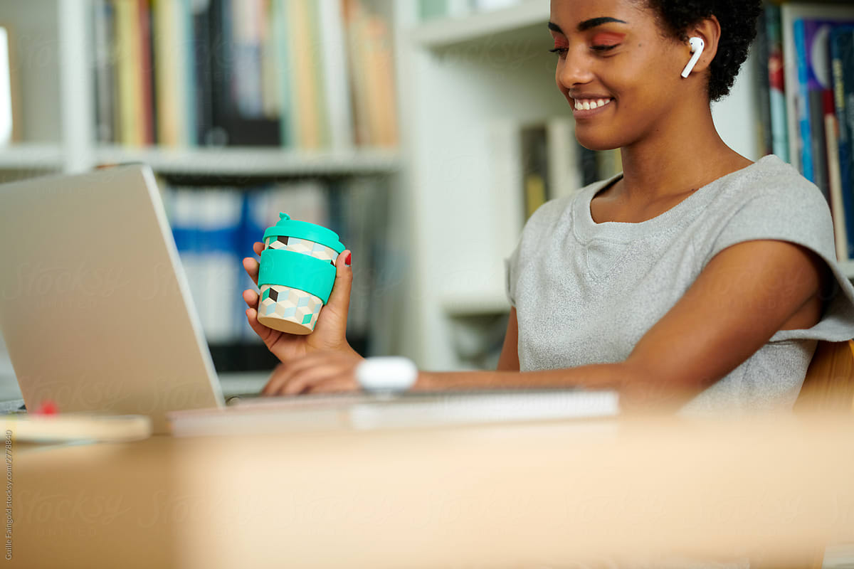 Cheerful black student using laptop in library