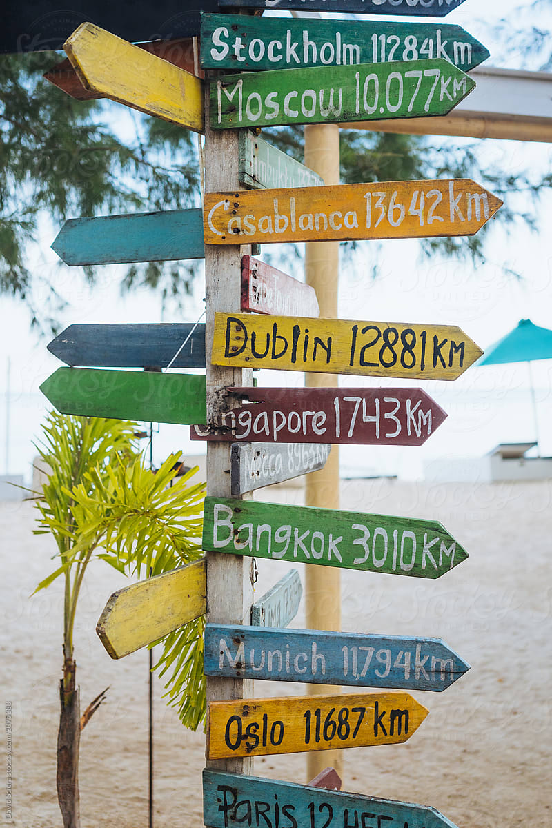 Travel destinations on wooden colourful sign at a beach