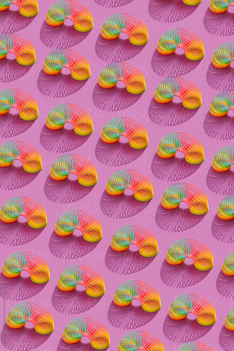 Pattern of rainbow helical spring toys on pink.