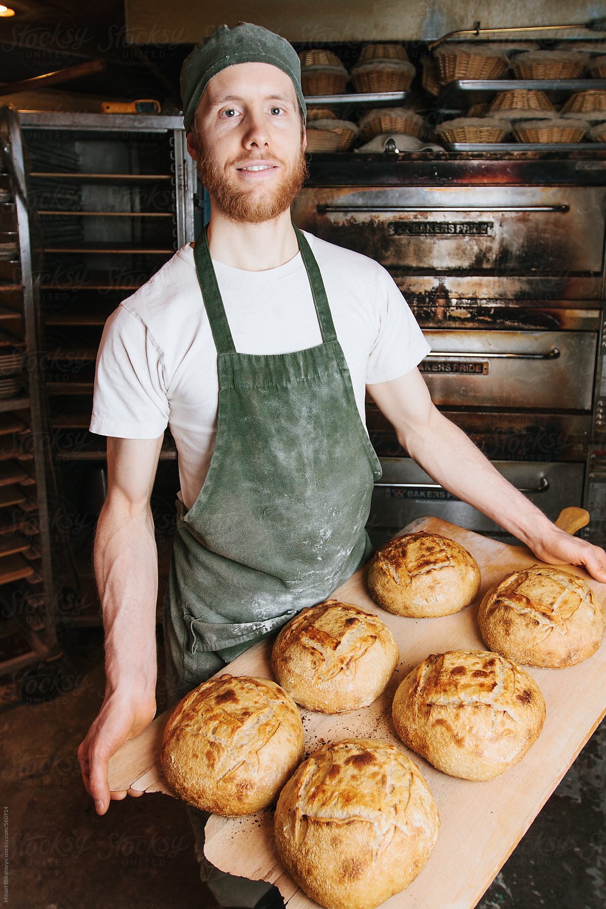 Baker posing with his freshly-baked bread at a small-scale, artisan bakery