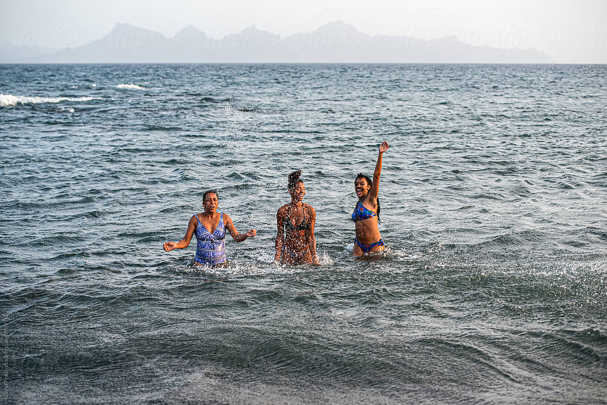 Women family in bikini splashing water in a volcanic beach