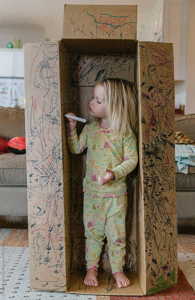 Child Playing with Cardboard Box and Writing on it
