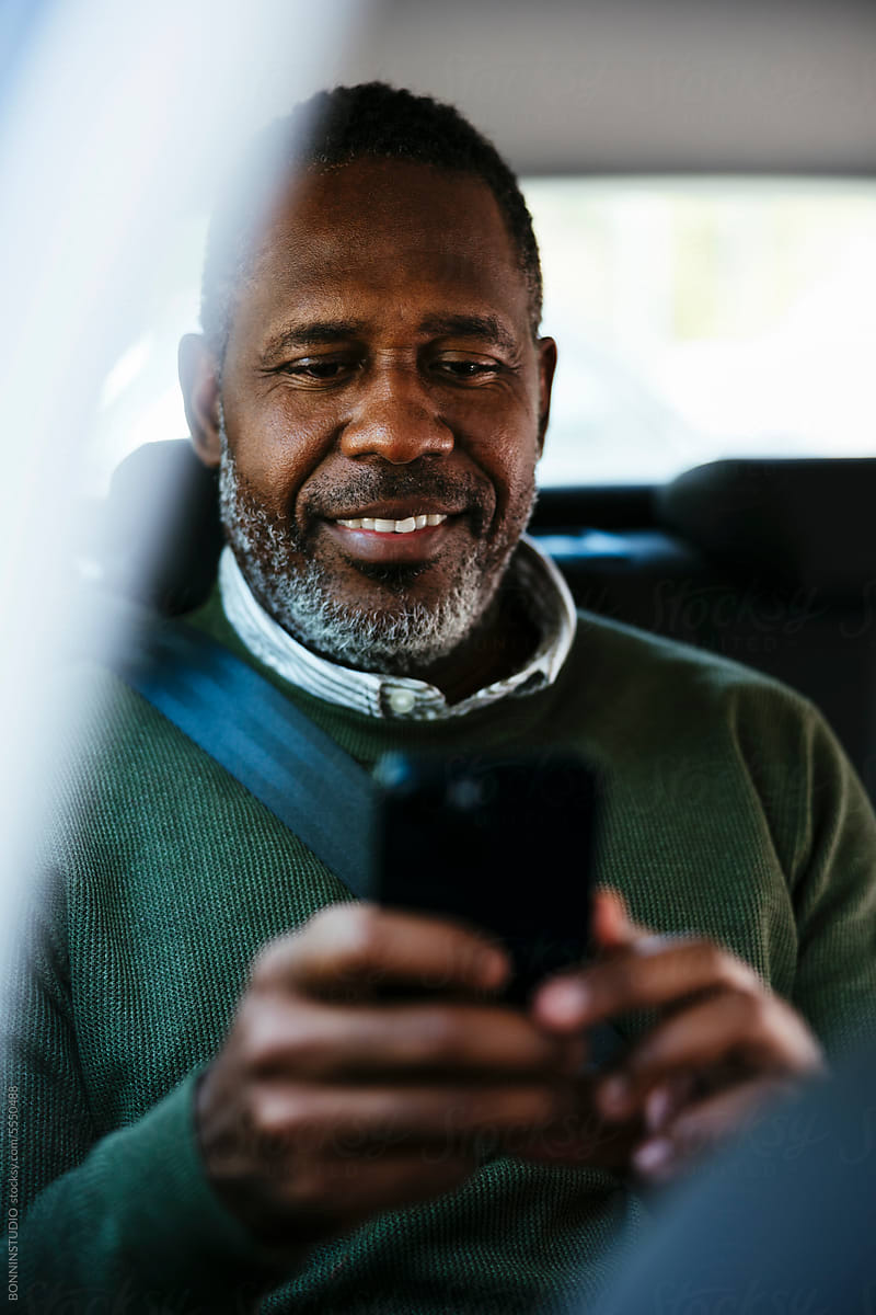 Smiling man using smartphone in car