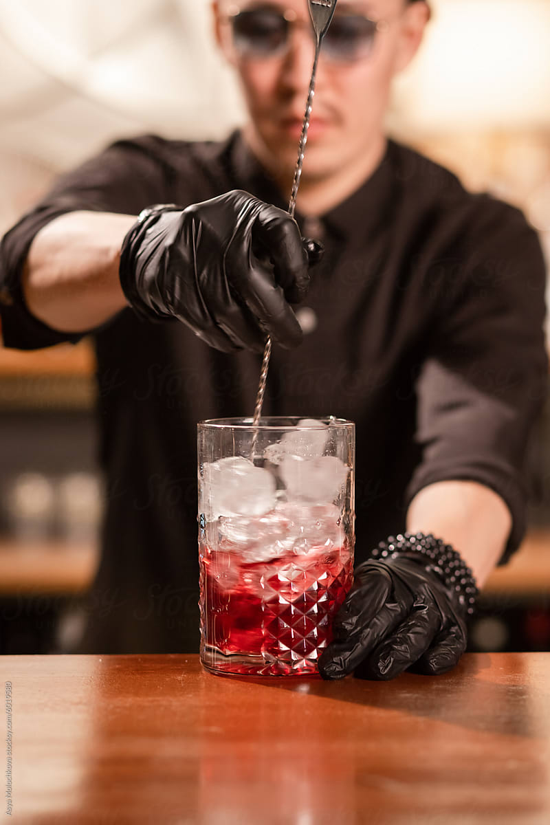 Barman is preparing cocktail in bar for client
