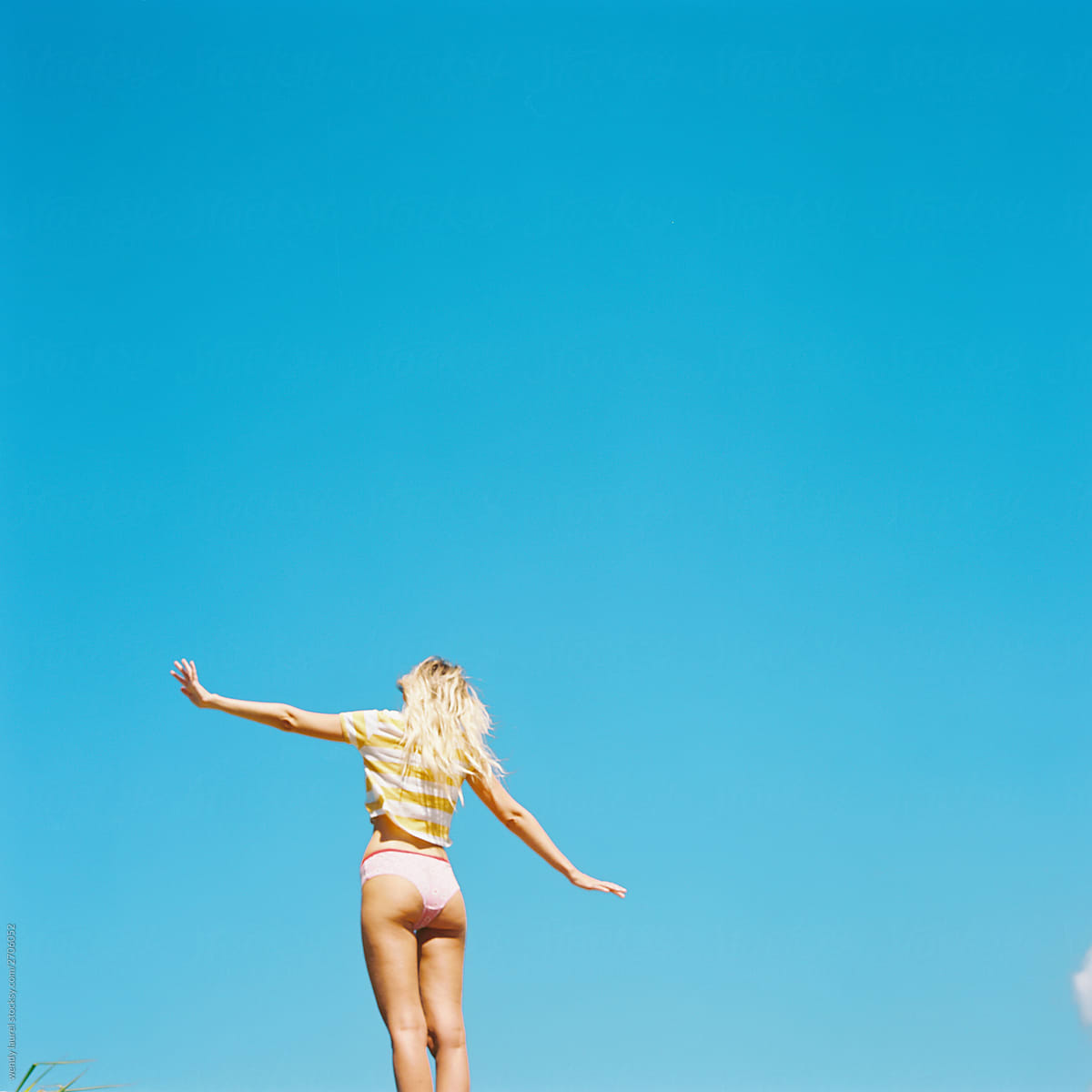 Blonde beautiful woman against bright blue sky in underwear and bra and striped tee
