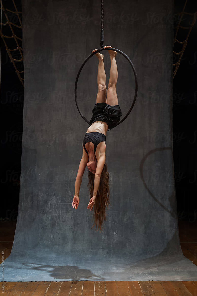 Aerial artist in a beautiful pose on a Lyra or Aerial hoop upside down