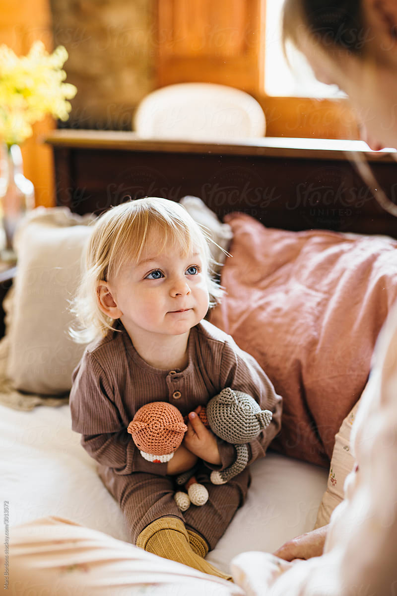 Toddler playing in her parents\' bed.