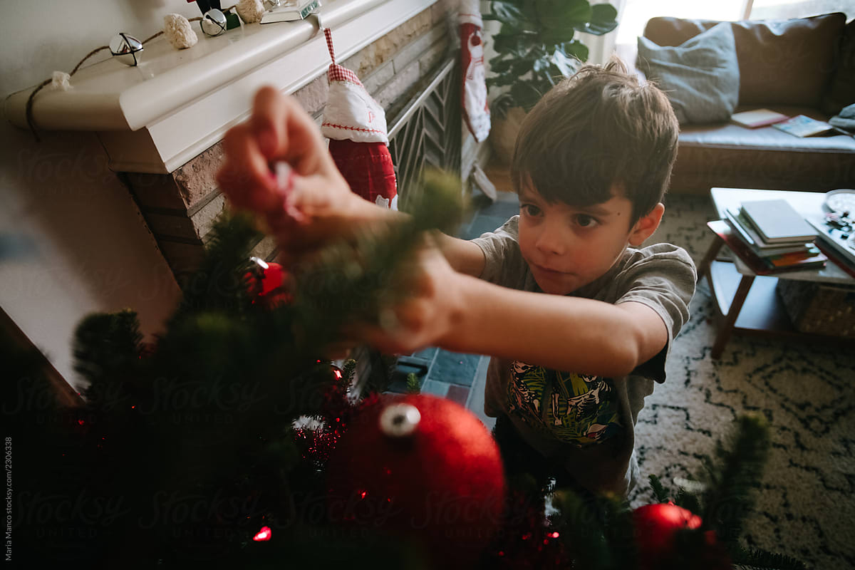 child decorating christmas tree inside home