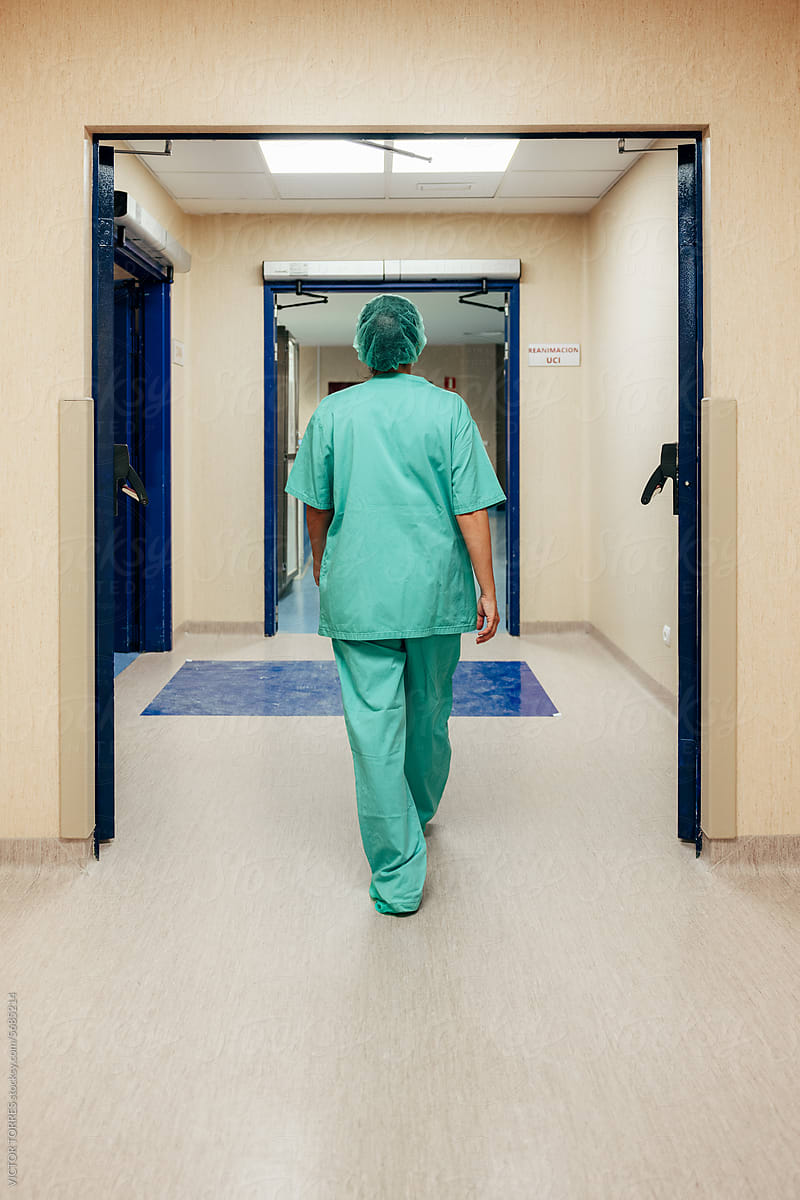 Anonymous doctor in scrubs walking in clinic corridor