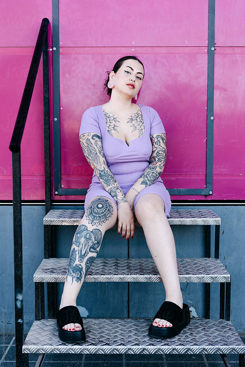 Tattooed curve model sitting on stairs