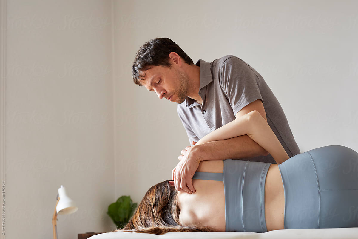 An osteopath applying pressure to upper back\'s point