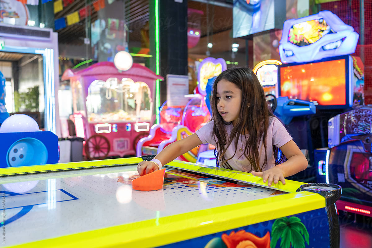 Energetic Play. Young Girl Enjoy Air Hockey Thrills at the Arcade Park
