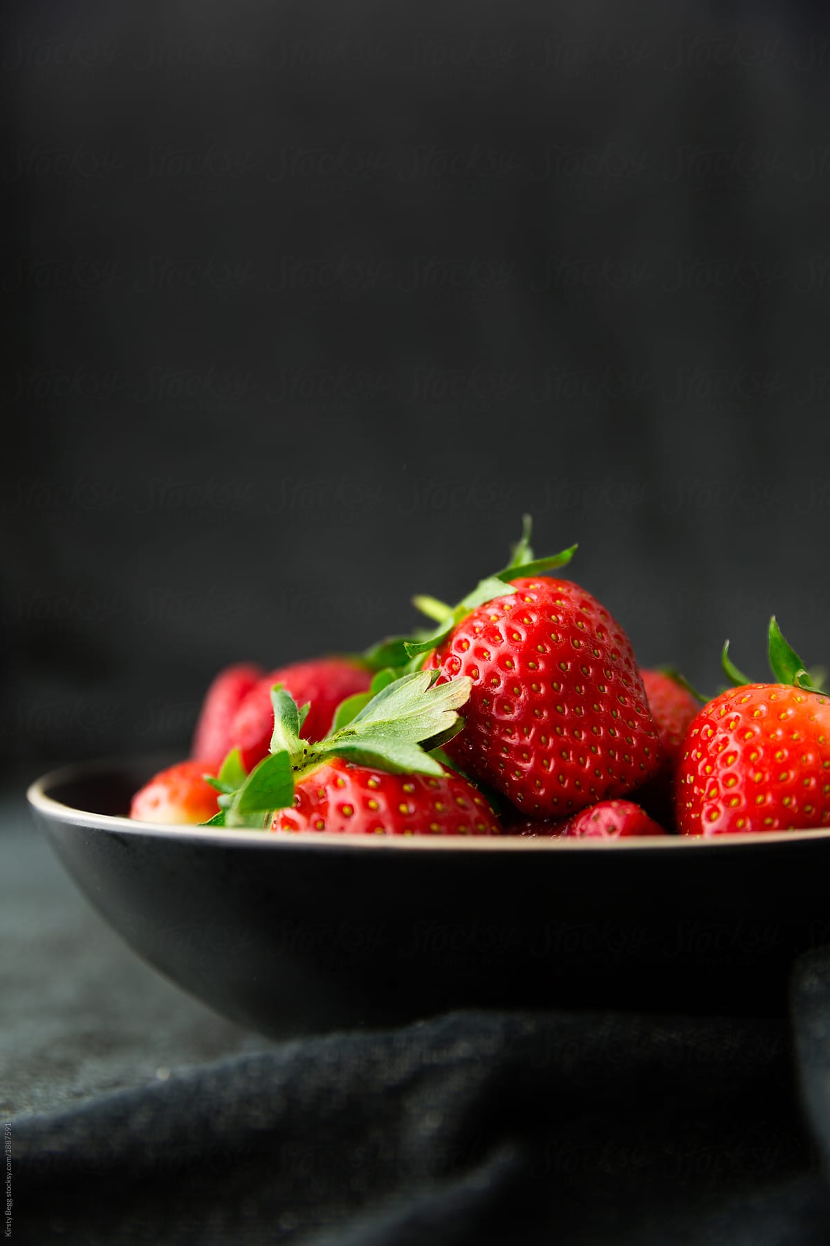 Vertical shot strawberries in black bowl