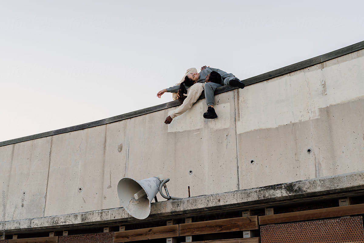 Friends laying down on top of wall next to megaphone