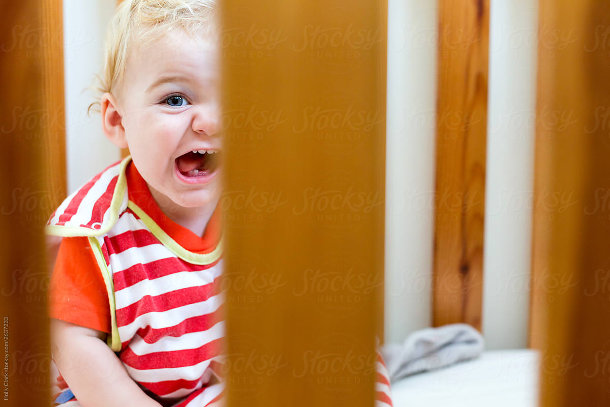 Blond boy laughs in crib