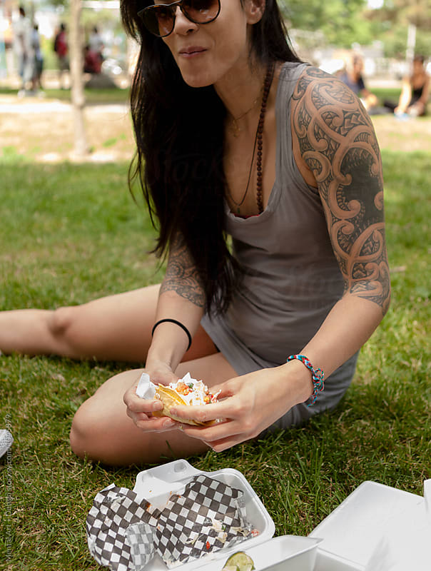 Pretty, fit, asian woman eating take out taco.