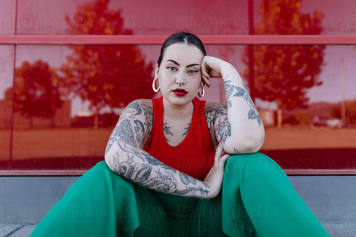 Tattooed woman leaning on hand and looking at camera