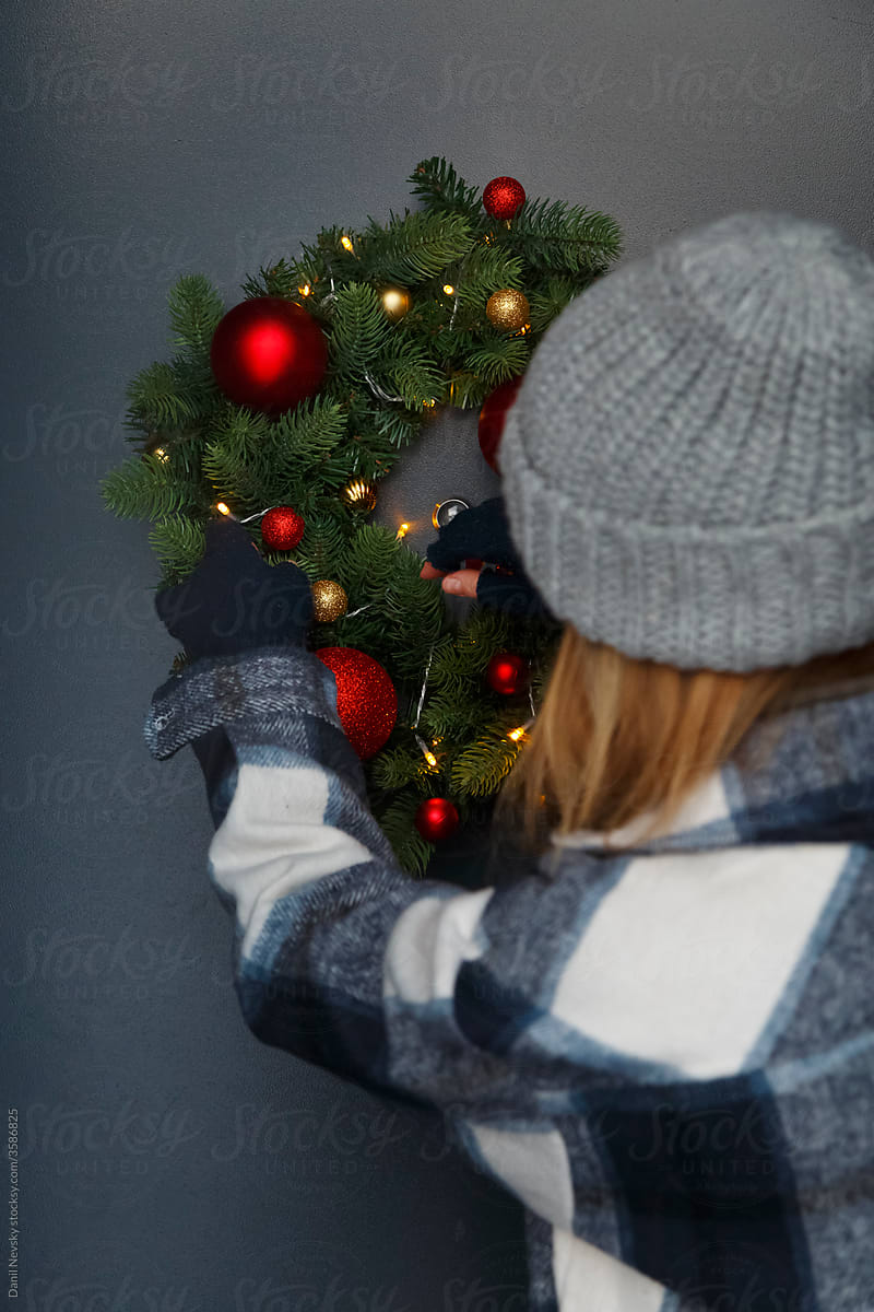 Unrecognizable female adjusting fairy lights on Christmas wreath