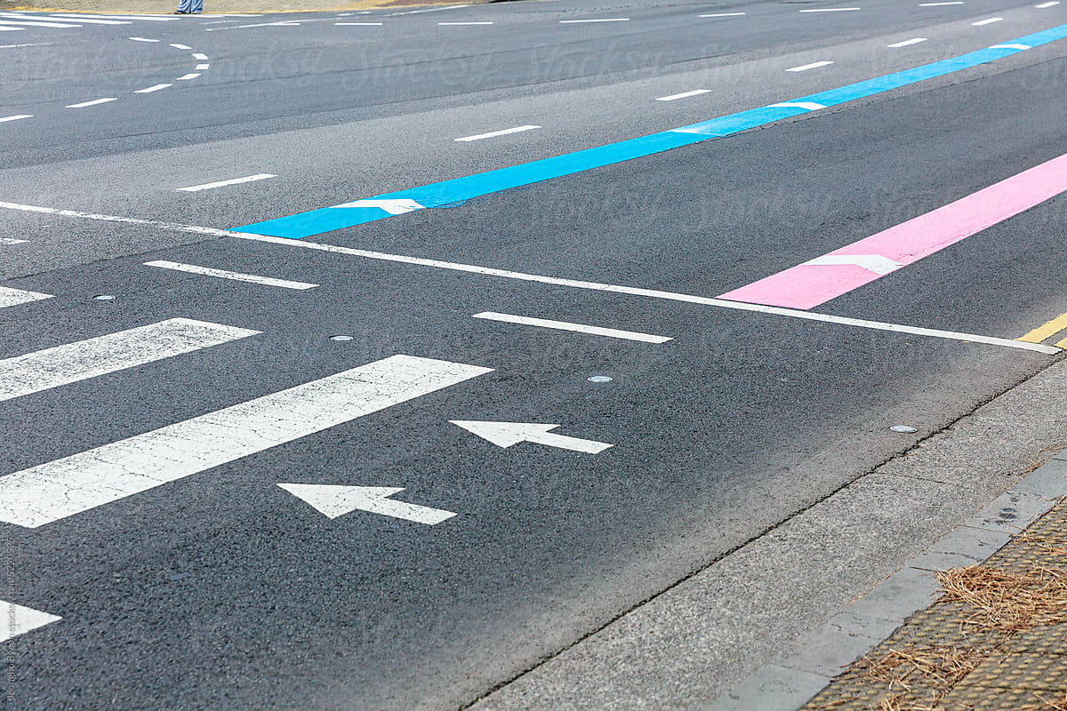 Pink and blue guide lines and arrows painted on the road.