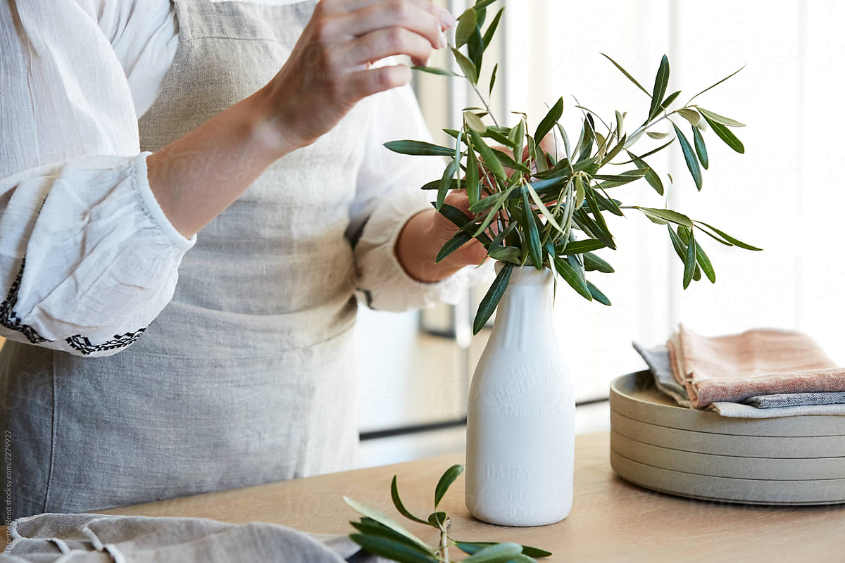 Woman arranging olive branches in a vase