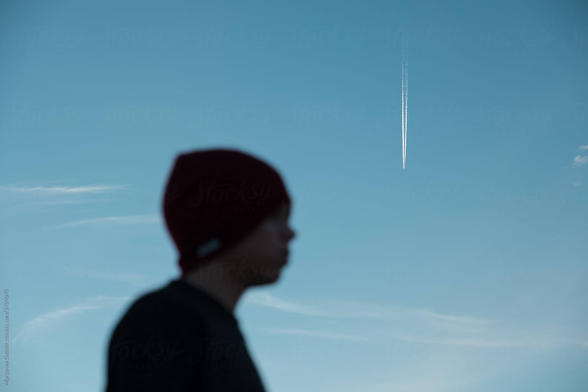 Silhouette of boy with Jet Contrails in the Sky