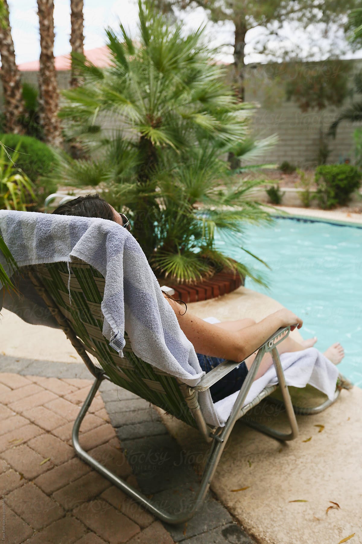 Woman reclines in retro lounge chair next to pool
